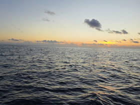 A serene view of the ocean at sunset, capturing the tranquil beauty of the water and sky.