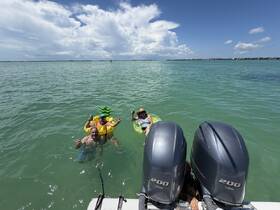 A lively group enjoys a fun day in the water, floating on colorful inflatables and sipping drinks — perfect for a summer getaway.