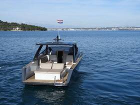 A sleek yacht is captured from the back, cruising through calm waters, showcasing its modern design and inviting seating area.