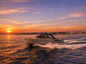 A sleek yacht glides through the water at sunset, showcasing its elegant design against a vibrant sky — perfect for luxury cruising.