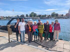 A cheerful group poses together at the harbor next to their boat, ready for an exciting adventure on the water.