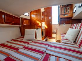Cozy interior of a boat cabin featuring comfortable striped seating and wooden finishes, perfect for relaxing during your nautical adventures.