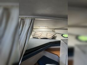 Cozy cabin interior featuring a comfortable sleeping area with striped pillows, perfect for relaxation on a boat.