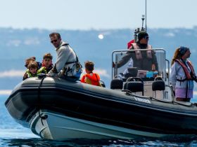 A family enjoys a day on the water aboard a boat, with children excitedly taking in the views — perfect for family adventures and creating lasting memories.