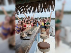 A lively group of friends celebrates together on a boat, showcasing the fun and excitement of a bachelorette party on the water.
