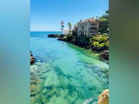 A stunning view of a picturesque coastline featuring a lighthouse and clear turquoise waters, perfect for showcasing beautiful destinations and scenic boat trips.