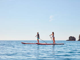 A couple enjoys paddleboarding on calm waters, showcasing a perfect day of adventure and relaxation on the water.