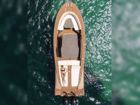 Aerial view of a woman sunbathing on the deck of a stylish boat, showcasing the perfect setting for relaxation on the water.