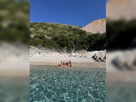 A group of friends enjoys a sunny day at the beach, relaxing and soaking up the sun by the crystal-clear waters — a perfect getaway for fun and relaxation.