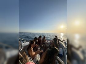 A group of friends enjoys drinks on a boat during sunset, capturing the essence of a perfect party experience on the water.