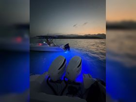 A serene sunset view featuring a boat with illuminated engines, perfect for evening cruises and water adventures.
