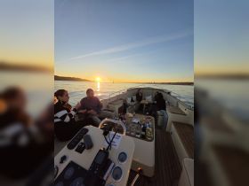 A group enjoys a sunset gathering on a boat, complete with cocktails and good company — the perfect setting for a memorable evening on the water.