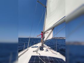 A person enjoys the thrill of sailing, standing at the bow of a yacht with arms outstretched, capturing the essence of adventure on the open water.