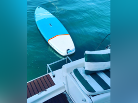 A vibrant paddleboard floats in clear waters next to a boat, showcasing the perfect water toy for fun and relaxation on your boating adventure.