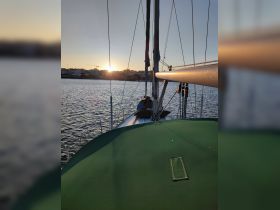 A serene view of a sailboat at sunset, with a guest relaxing on the deck, creating a perfect backdrop for tranquil sailing experiences.
