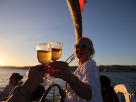 Guests toast with cocktails against a stunning sunset backdrop, capturing the essence of celebration and camaraderie on the water.