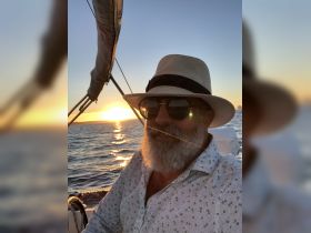A man enjoys a serene sunset while sailing, capturing the essence of relaxation on the water — perfect for sunset cruises.