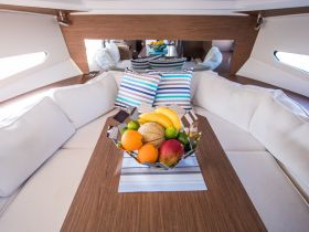 A beautifully arranged dining area inside a yacht, featuring a bowl of fresh fruits and comfortable seating, perfect for enjoying meals while cruising.
