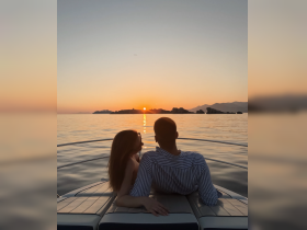 A couple enjoys a romantic sunset view from the deck of a yacht, creating the perfect atmosphere for a sunset cruise.