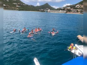 A lively group enjoys a refreshing swim in crystal-clear waters, showcasing a fun day of snorkeling and relaxation under the sun.