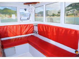 Interior view of a boat cabin featuring comfortable red seating, perfect for relaxing during a day on the water.