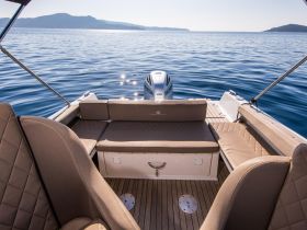 A cozy interior view of a boat's seating area, showcasing comfortable cushions and a serene water backdrop, perfect for relaxing on the water.