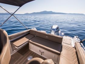 A cozy interior view of a boat featuring comfortable seating and a sleek helm, perfect for relaxing on the water.