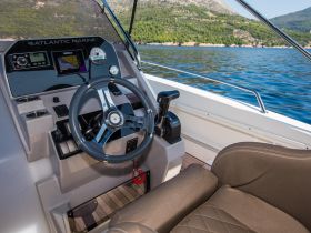 A detailed view of the helm and seating area inside a boat, showcasing modern controls and a comfortable design, perfect for navigating the open waters.