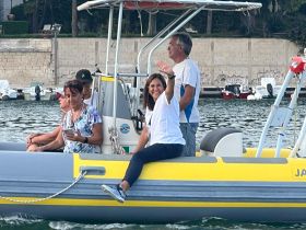 A cheerful group enjoys a boat ride, with one woman waving at the camera — a perfect moment capturing the joy of being on the water.