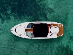 Aerial view of a sleek boat cruising over crystal-clear waters, showcasing its elegant design and spacious deck — perfect for luxurious outings on the water.