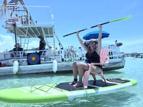 A joyful woman celebrates on a paddleboard, showcasing the fun and vibrant atmosphere of a day on the water with friends.