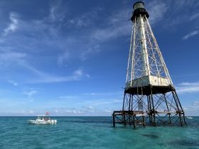 A scenic view featuring a boat near a historic lighthouse, showcasing the beauty of the ocean and inviting exploration of coastal landmarks.