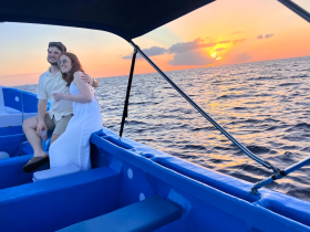 A couple enjoys a romantic moment on a boat at sunset, capturing the essence of love and adventure on the water.