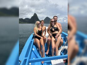 A cheerful group of friends enjoys a sunny day on a boat, surrounded by stunning coastal scenery — perfect for memorable adventures and beach outings.