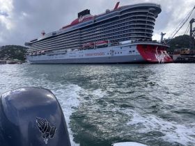 A stunning view of the Virgin Voyages cruise ship docked in the harbor, showcasing its modern design and vibrant colors against a scenic backdrop.