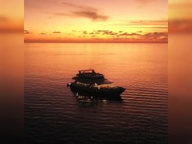 A stunning aerial view of a luxurious yacht cruising during a vibrant sunset, showcasing the beauty of evening boat adventures.