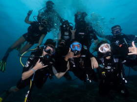 A lively group of divers poses underwater, showcasing the excitement of scuba diving adventures — perfect for thrill-seekers and marine enthusiasts.