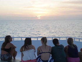 A group of friends enjoys a stunning sunset view from the deck of a boat, creating a perfect backdrop for memorable moments on the water.