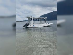 A sleek boat is docked in shallow waters, surrounded by a scenic backdrop of mountains — perfect for exploring coastal areas.