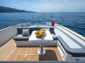 A beautifully arranged seating area on a yacht, featuring a table with a basket of fresh fruits, perfect for enjoying meals while cruising on the open water.