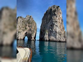 A stunning view of towering rock formations at sea, with a boat in the foreground, showcasing the breathtaking coastline — perfect for exploring iconic landmarks.