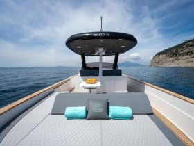 A beautifully designed lounge area on a Gozzo 35 boat, featuring plush seating and a table with fresh fruit, perfect for relaxing on the water.