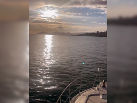 A serene sunset view from the bow of a boat, reflecting shimmering light on the water, perfect for capturing the tranquility of a boating experience.