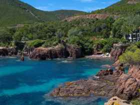 A stunning view of a rocky coastline with crystal-clear waters and lush greenery, perfect for exploring hidden beaches and enjoying nature's beauty.