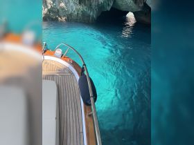 A stunning view from the deck of a boat, showcasing the vibrant turquoise waters and the entrance to a cave — perfect for exploring hidden gems on the water.