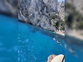 Two friends enjoy a refreshing swim in the crystal-clear waters near stunning cliffs, capturing the essence of a perfect summer day on the water.