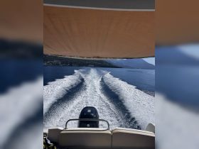 A view from the back of a boat cruising through calm waters, showcasing the wake and scenic mountain backdrop — perfect for adventure seekers and boating enthusiasts.