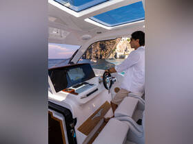 A man navigates the helm of a luxurious boat, showcasing the modern console and spacious cabin design, perfect for comfortable cruising.