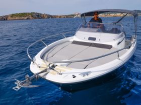 A sleek speedboat navigates through clear waters, showcasing its stylish design and spacious seating — perfect for a day on the water.