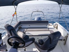 Interior view of a well-appointed boat helm and seating area, showcasing comfortable seating and a sleek design, perfect for a day on the water.